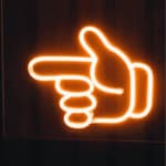 insegna luminosa con una mano con indice puntato che indica a sinistrra