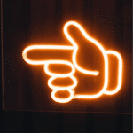insegna luminosa con una mano con indice puntato che indica a sinistrra